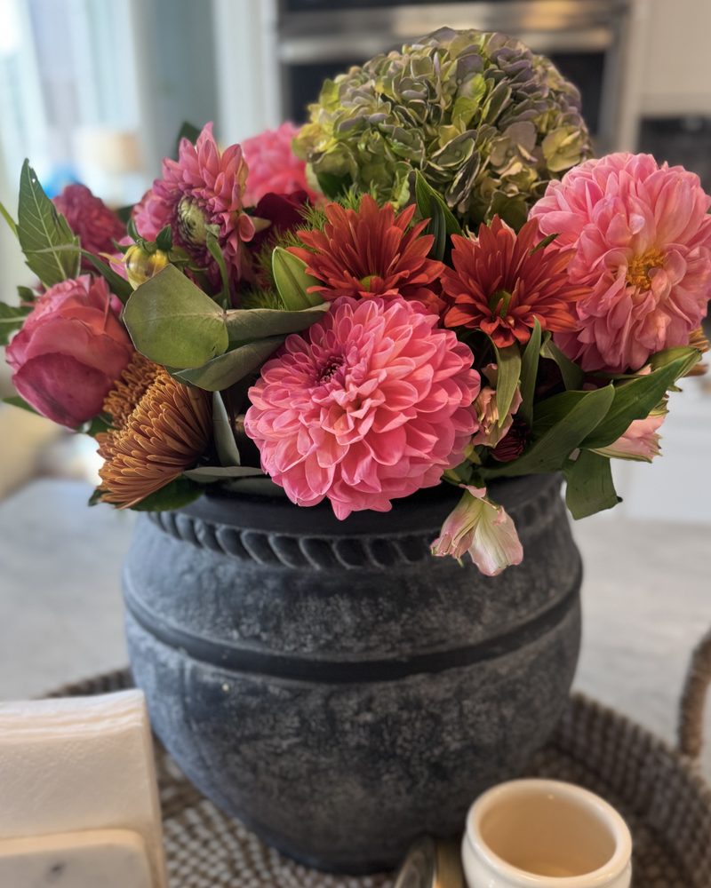 Pink and red dahlias and hydrangeas in a dark stone vase